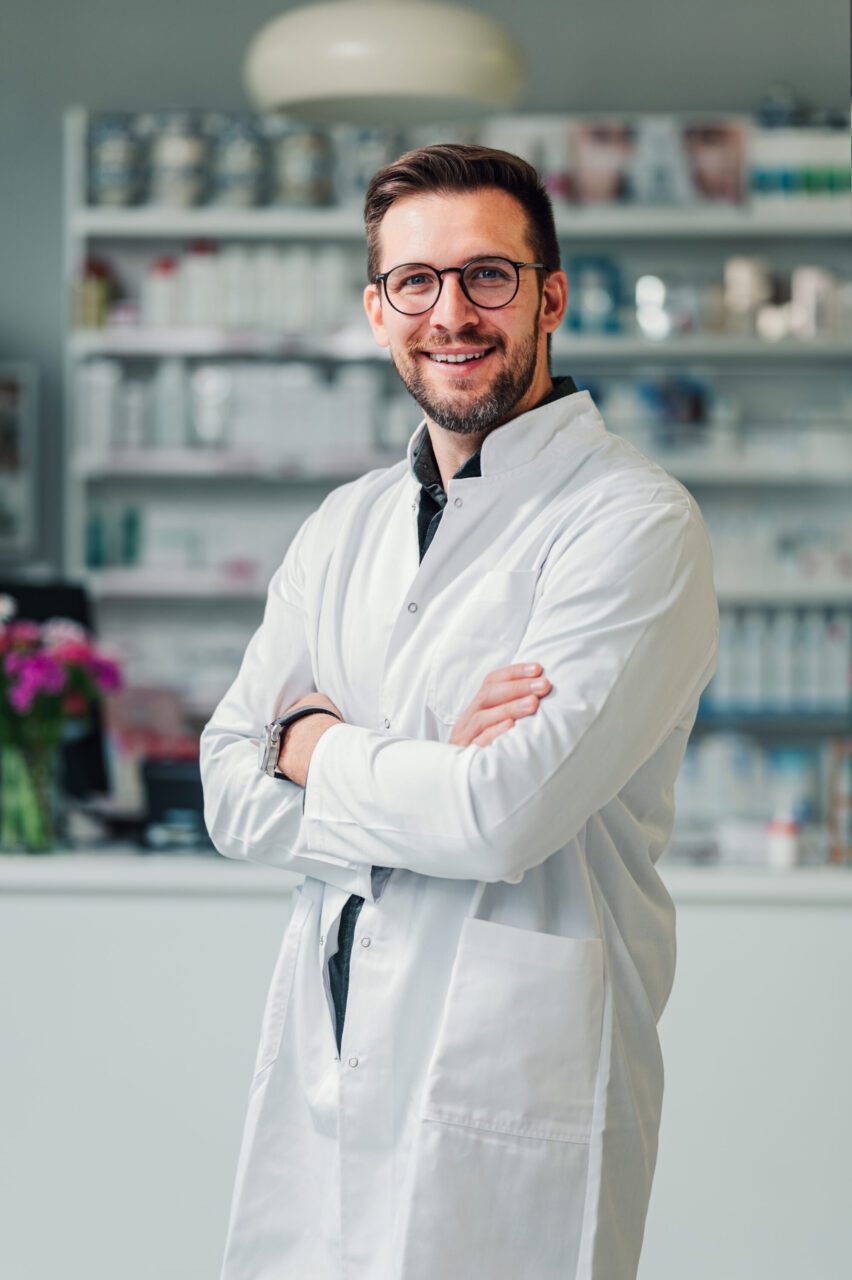 a-pharmacy-expert-is-standing-in-the-drug-store-and-smiling-at-the-camera-